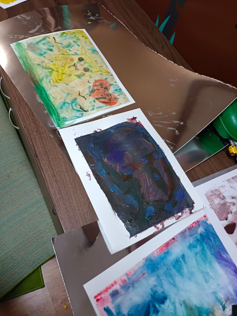 Zdjęcie przedstawia dokumentację warsztatów plastycznych. Dzieci malują akwarelami.